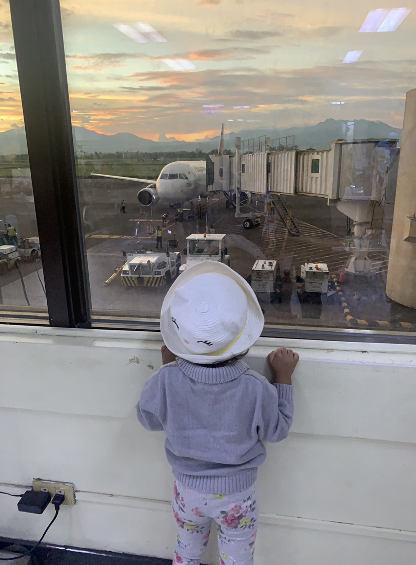 toddler looking out the window to see the airplane in the airport